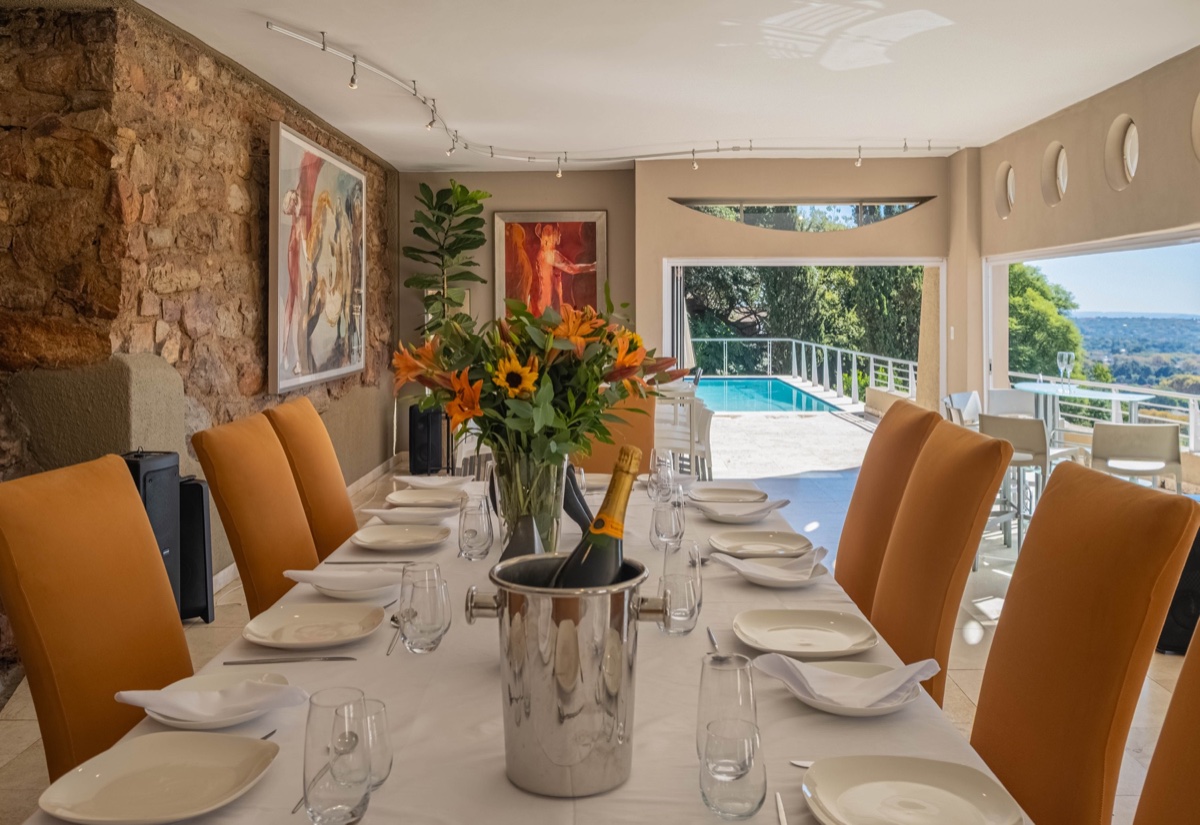 Event dining table arranged inside Cliffside with the pool deck beyond