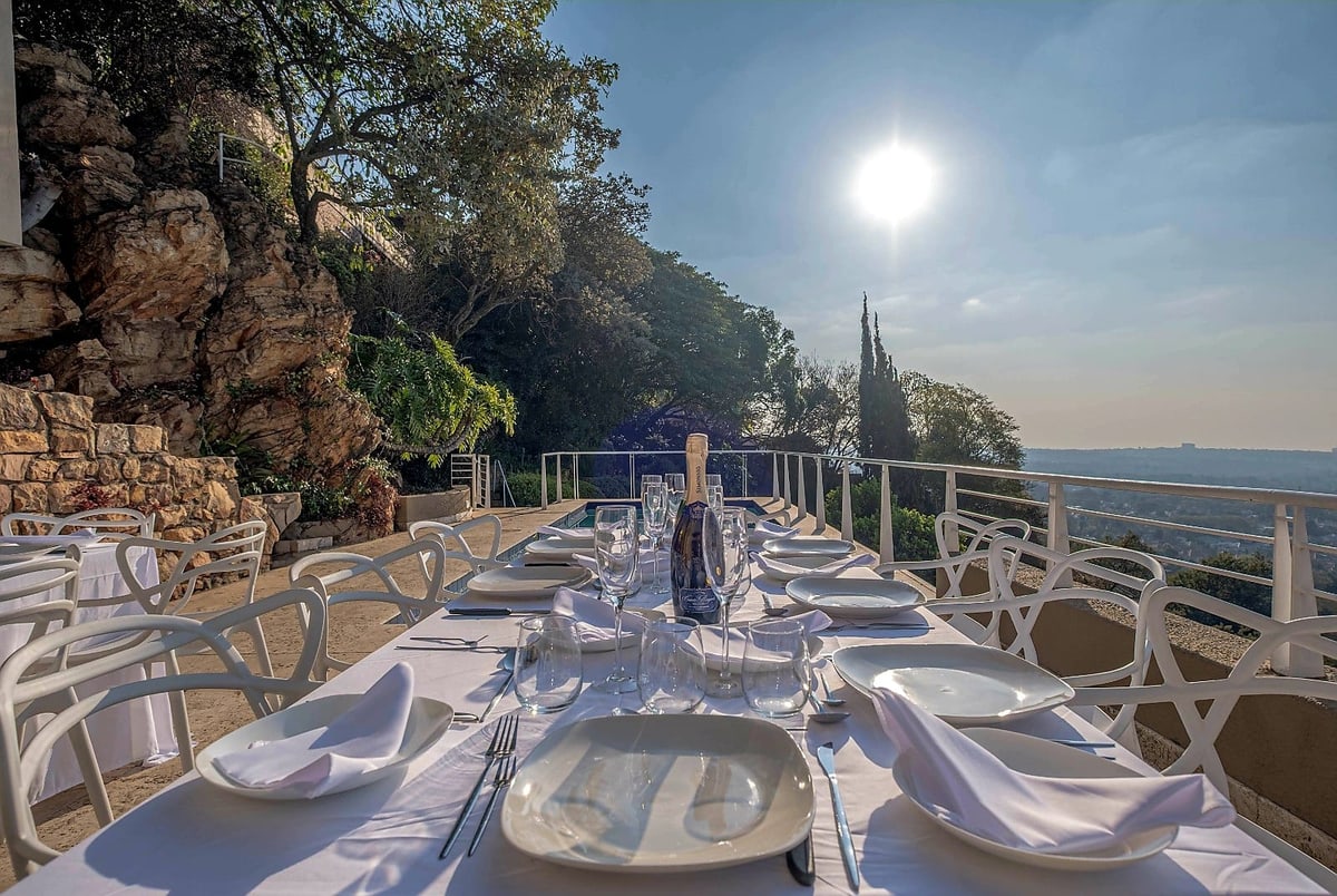 Outdoor dining table set on Cliffside's rock-framed city-view deck