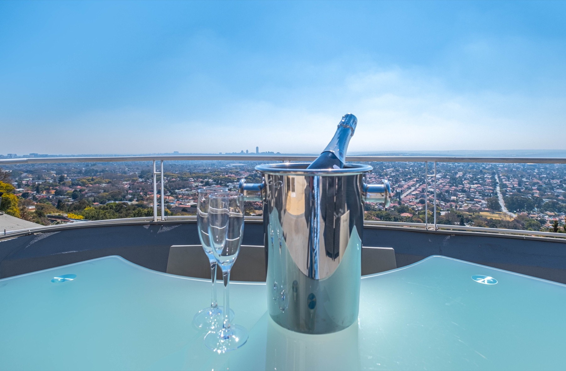 Champagne cooler on a glass table with Johannesburg in the distance