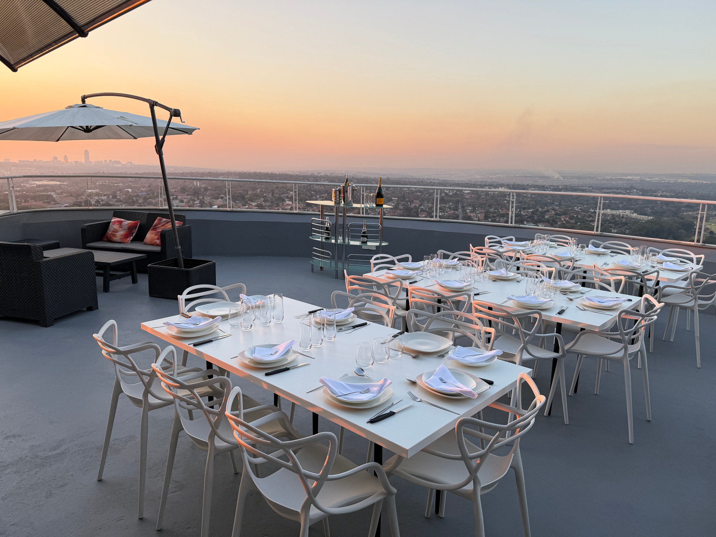Dining tables, lounge seating and a portable bar arranged on the Horizons deck at sunset