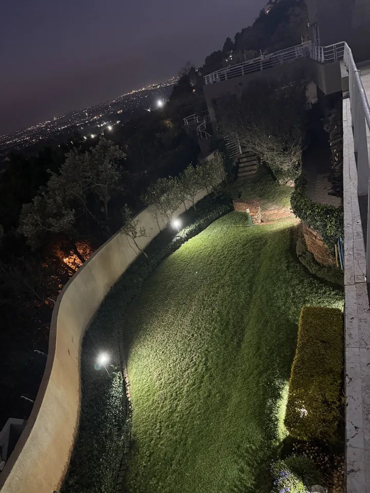 Elevated night view of a curved lawn and the Johannesburg lights beyond